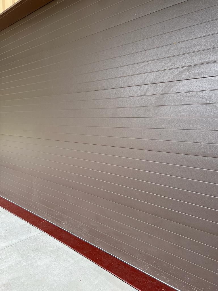 A close up of a brown garage door with a red trim.