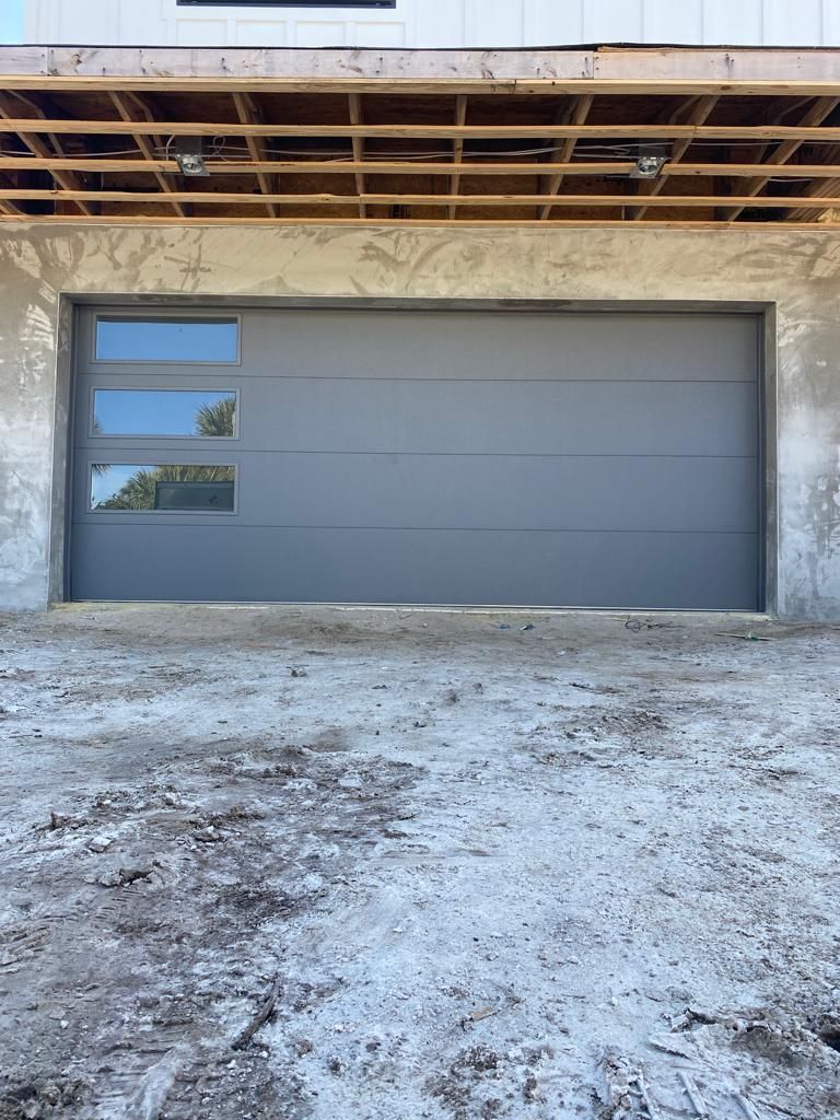 A garage door is being installed on the side of a house under construction.