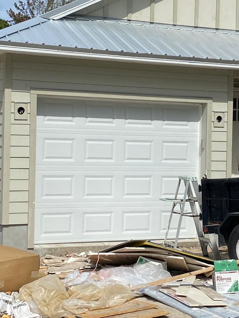 A white garage door is being installed on a house.