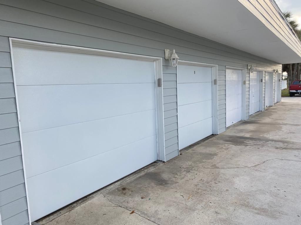 A row of white garage doors on the side of a building
