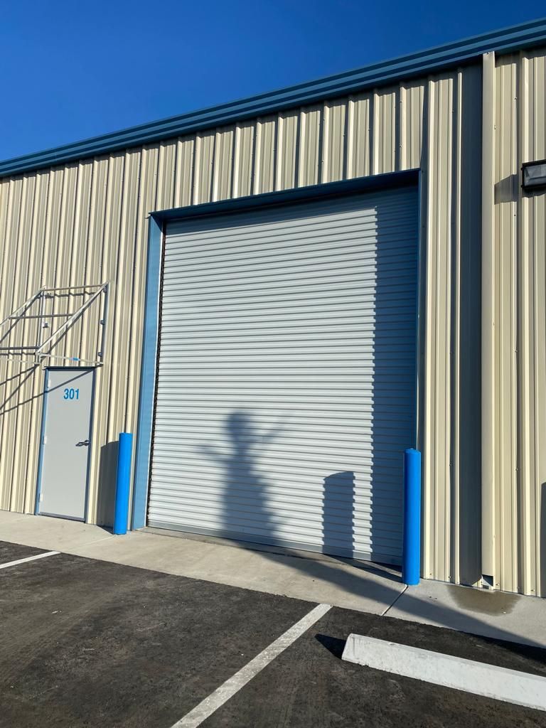 A white building with a blue garage door and stairs