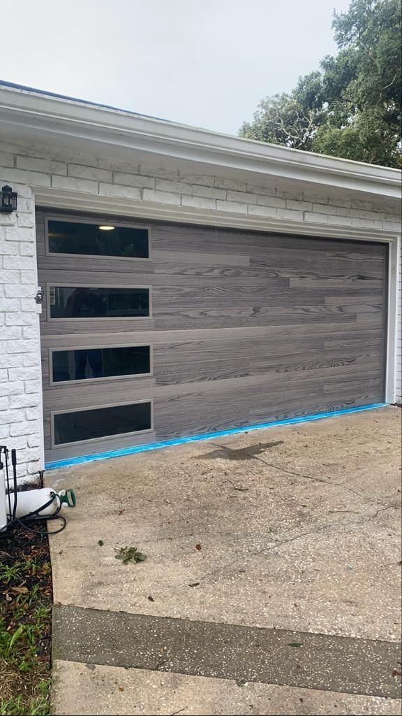 A garage door is being installed on a white brick house.