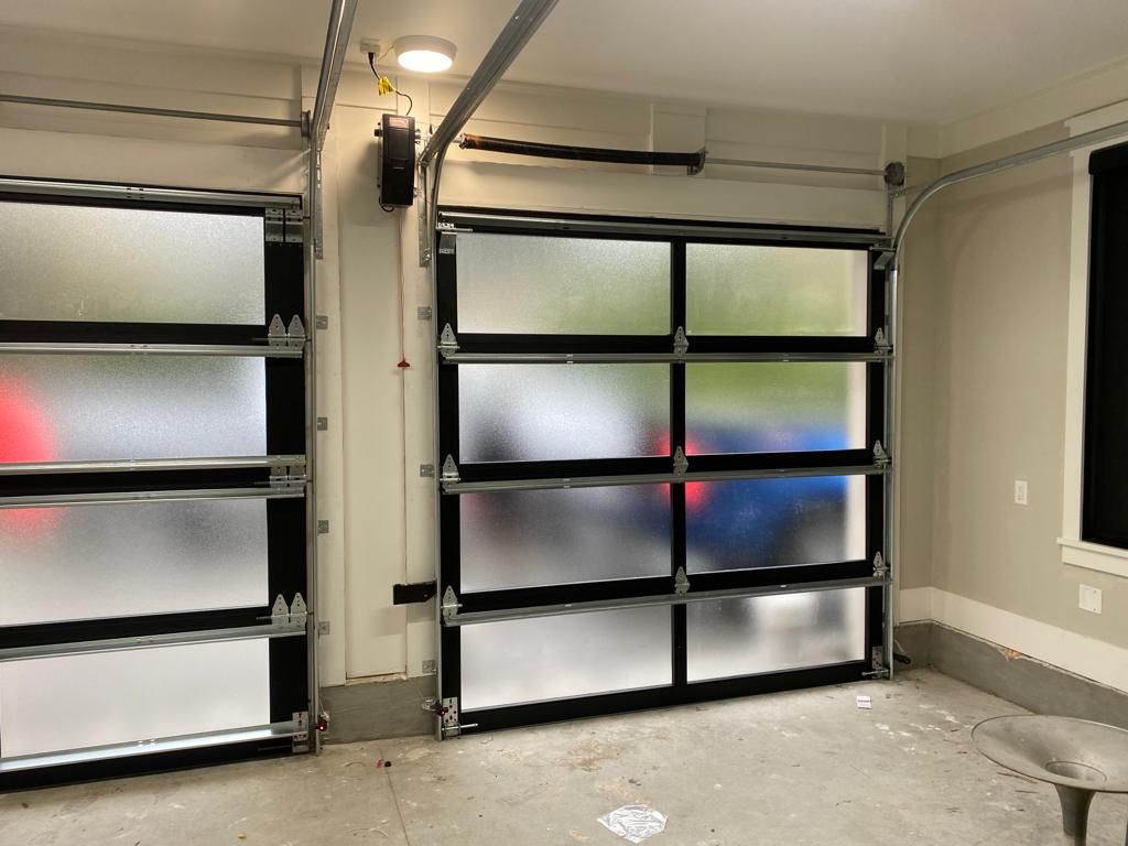A garage with a glass garage door and a car parked in the background.