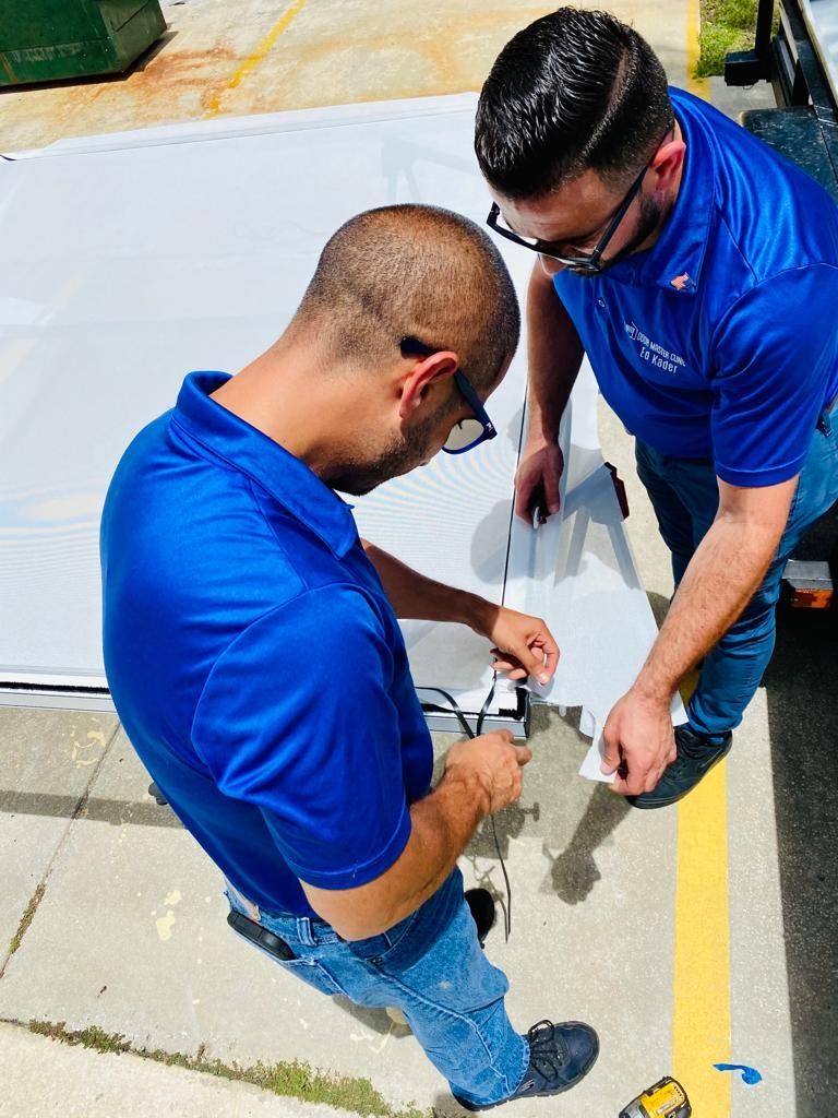 Two men in blue shirts are working on a piece of paper.