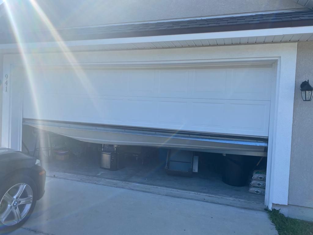 A car is parked in front of a garage door that is open.