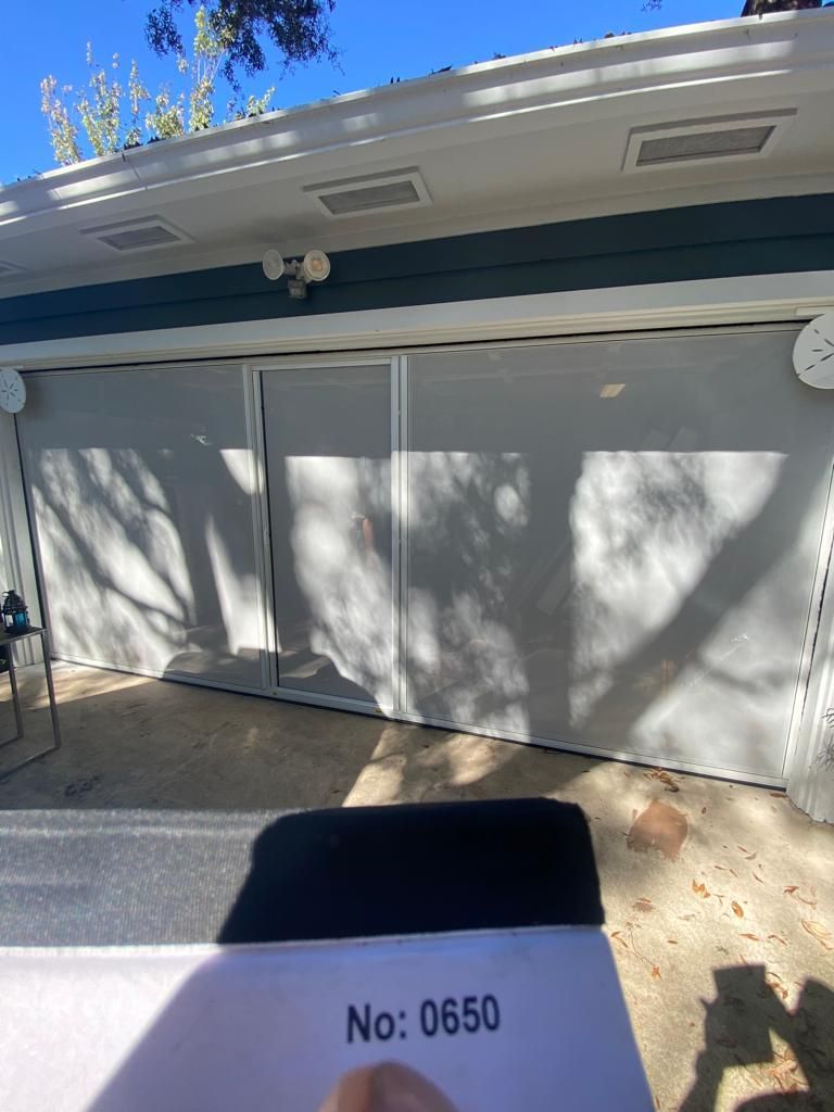 A person is holding a piece of paper in front of a garage door.