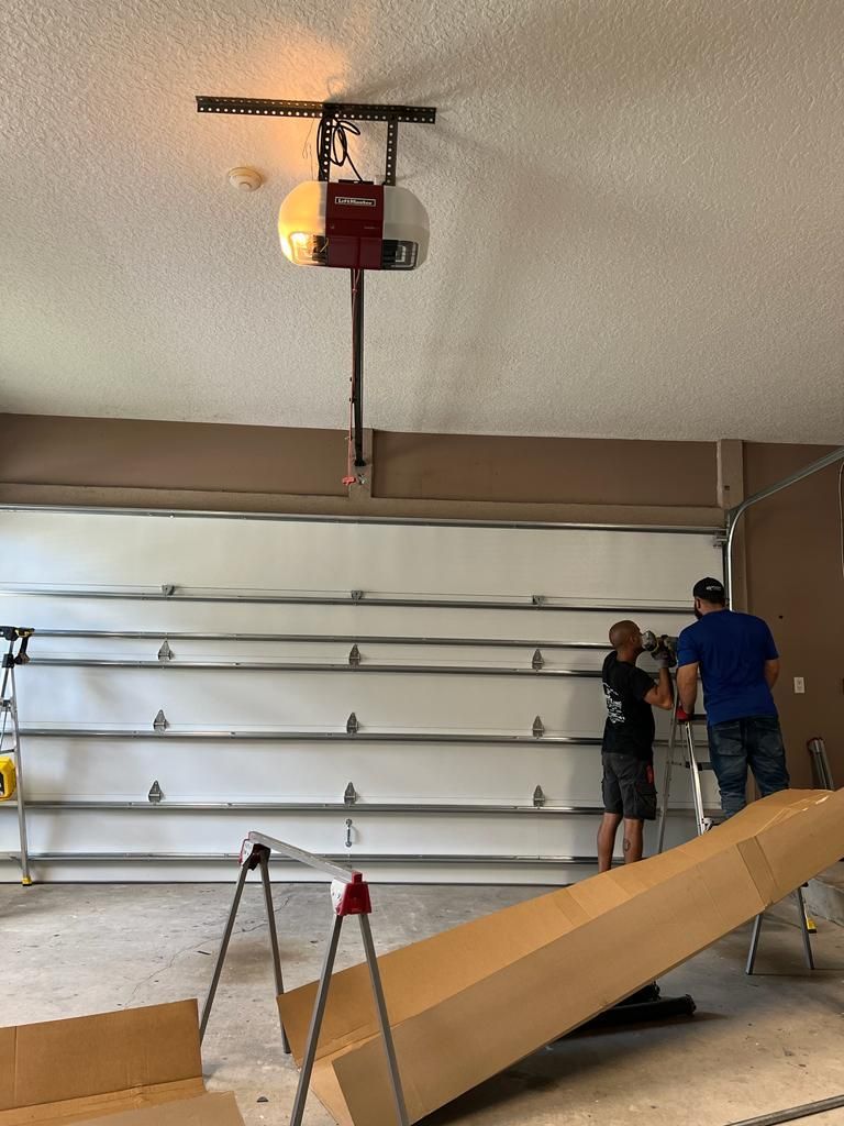 Two men are working on a garage door opener in a garage.