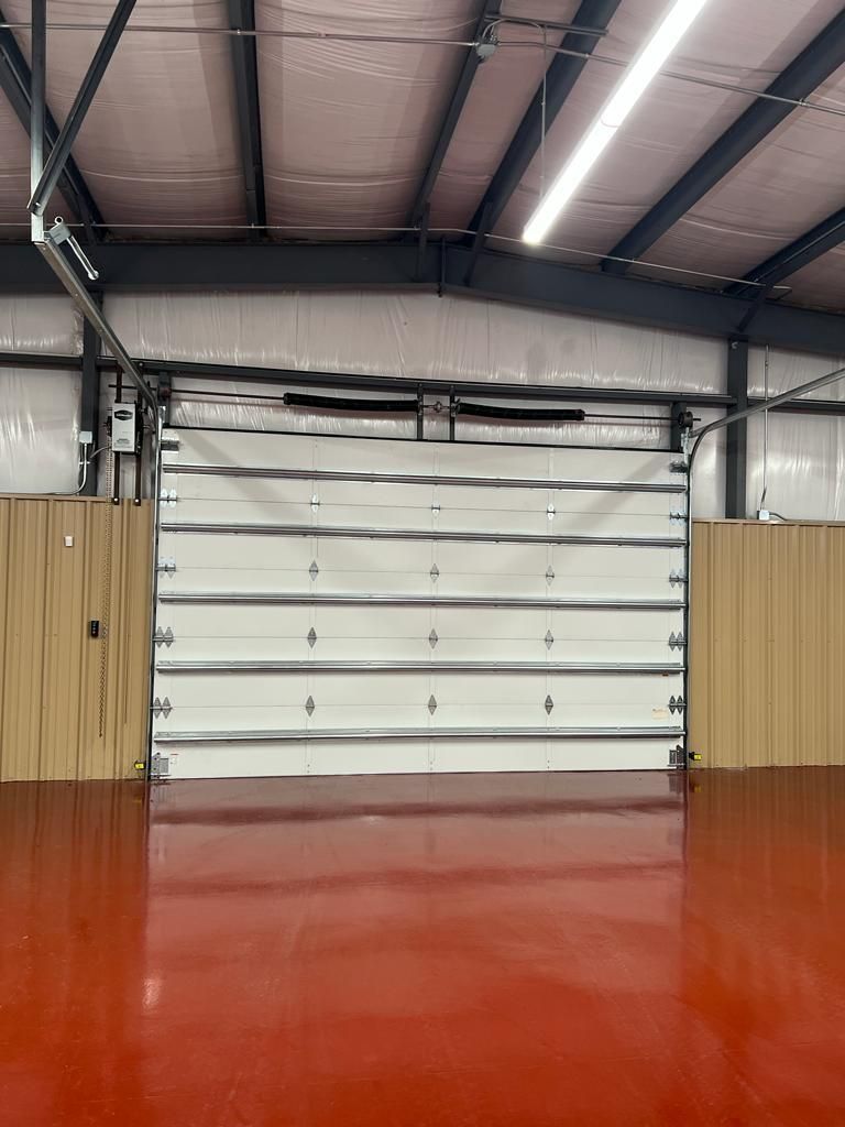 A garage with a white garage door and a red floor