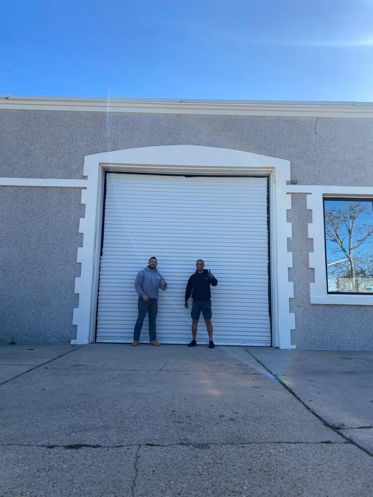 Two men standing in front of a large garage door