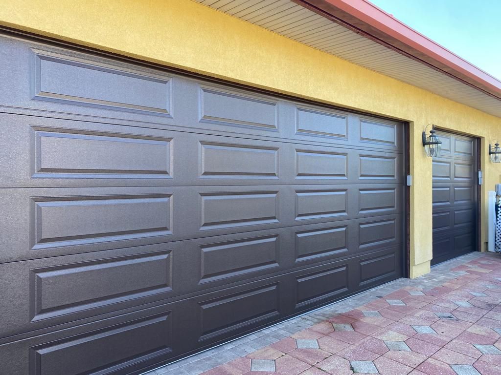 A yellow house with two brown garage doors on it.