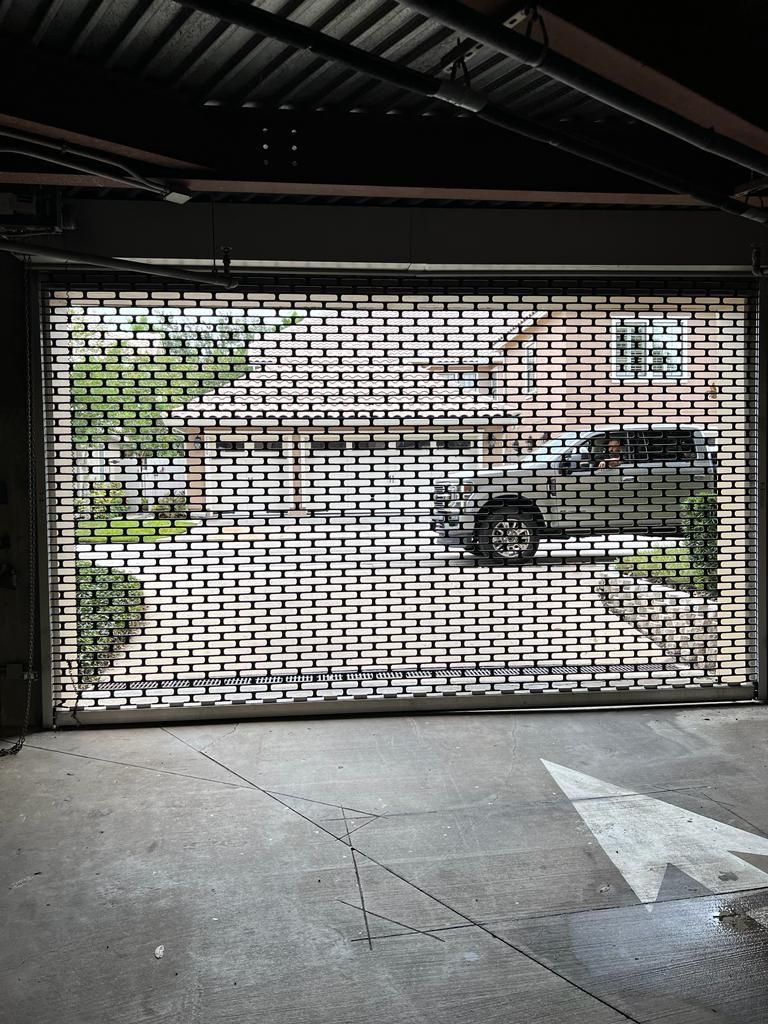 A car is parked in a parking garage with a garage door open.