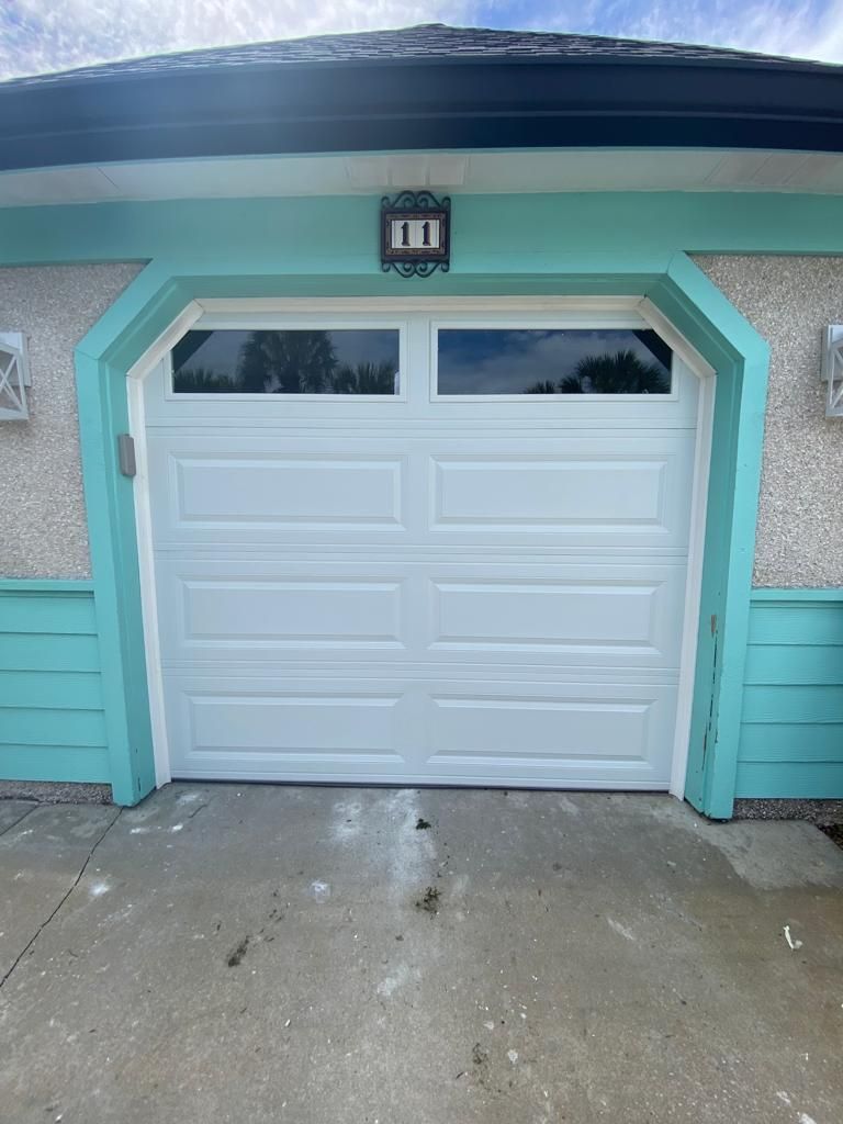 A white garage door is on the side of a house.
