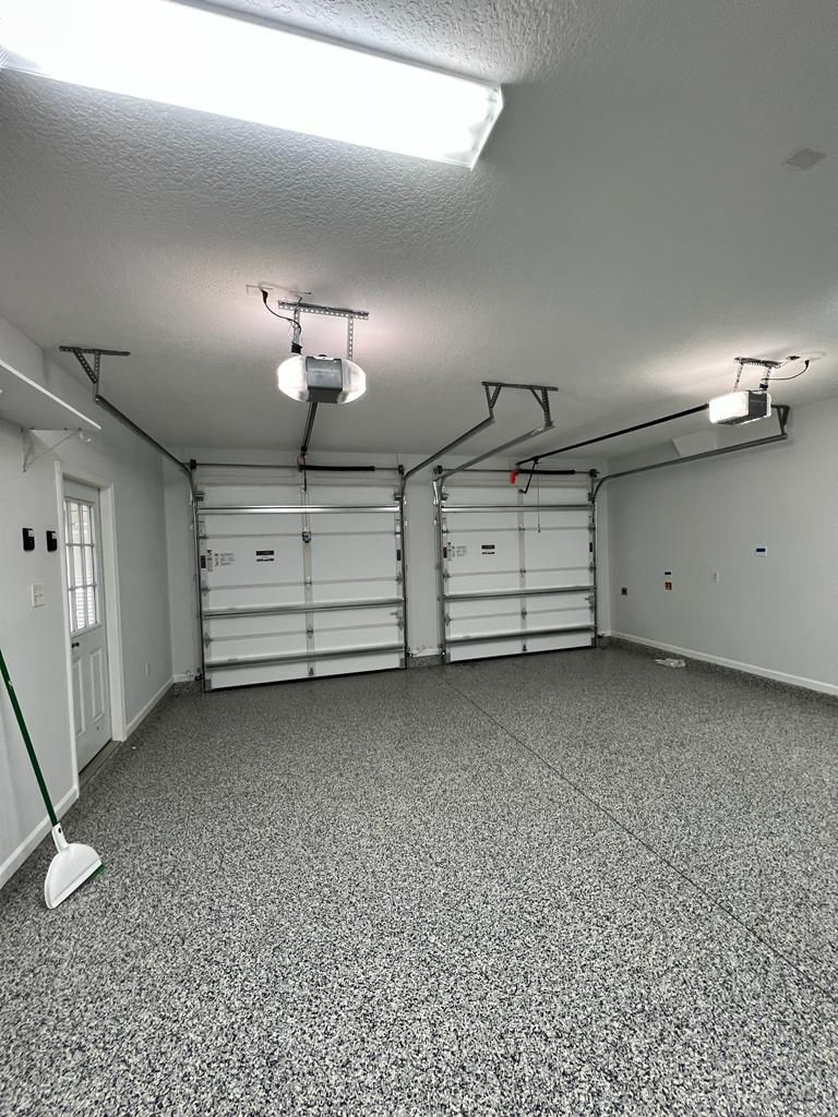 A large empty garage with two garage doors and a broom.