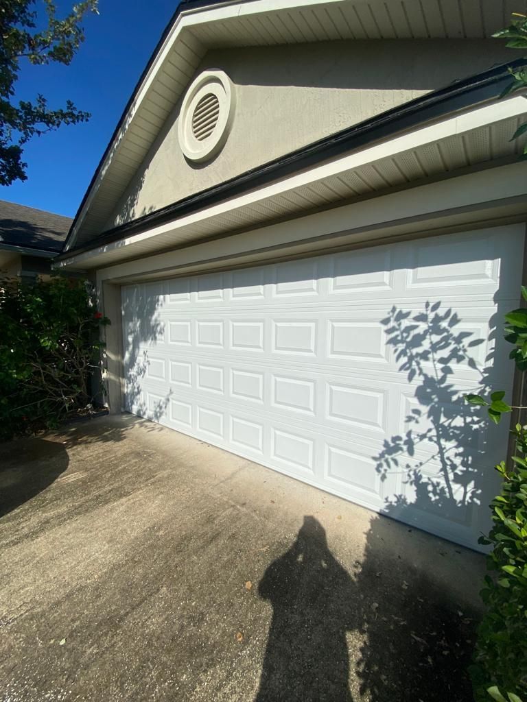 A white garage door is sitting in front of a house.