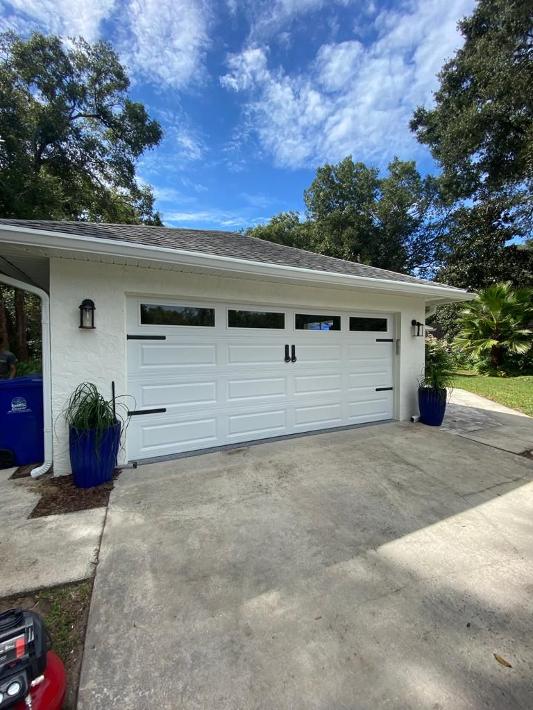 A white garage door is sitting in the driveway of a house.