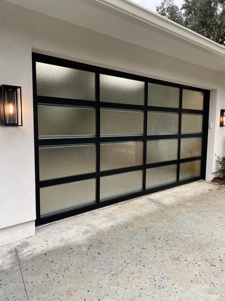 A garage door with a black frame and frosted glass