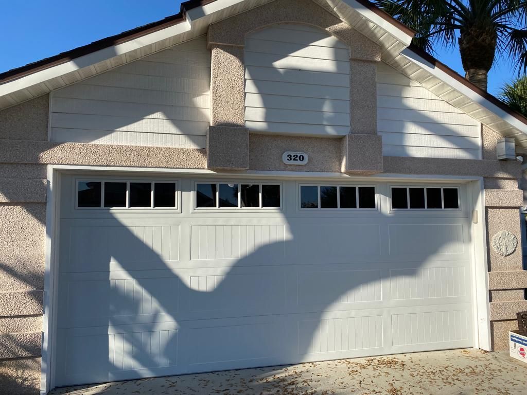 A white garage door is on the side of a house