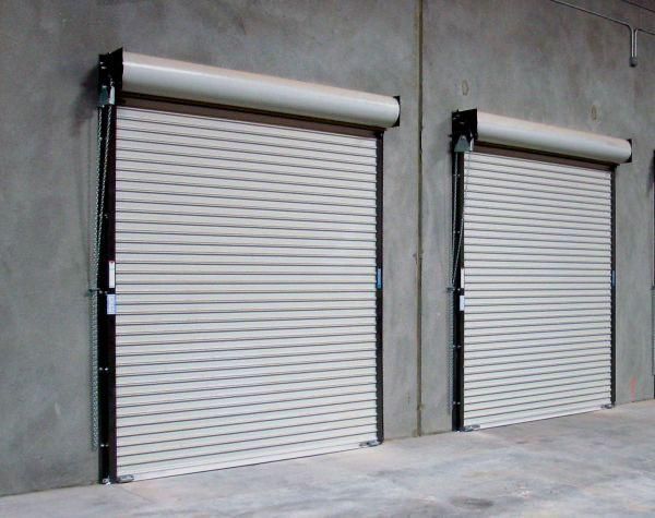 Two white roller shutter doors on a concrete wall