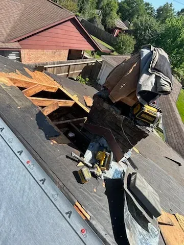 Roof repair in progress: hole in roof, debris scattered, power tools, partially covered with tarp.