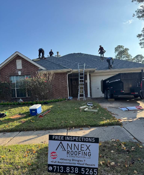 Roofers working on a house roof, Annex Roofing sign in the foreground.