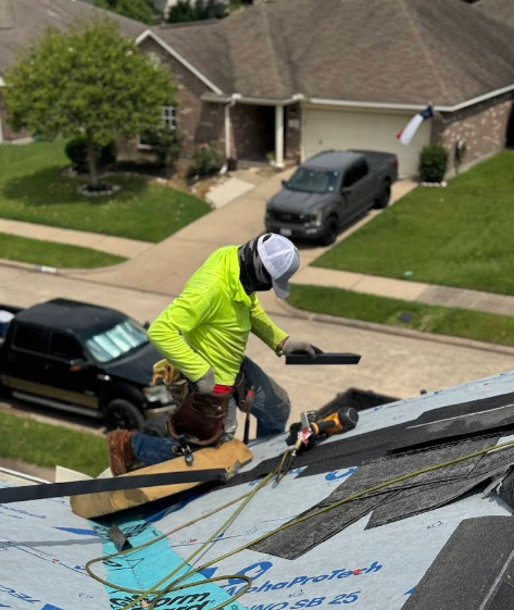 Roofer wearing a neon yellow shirt works on a residential roof.