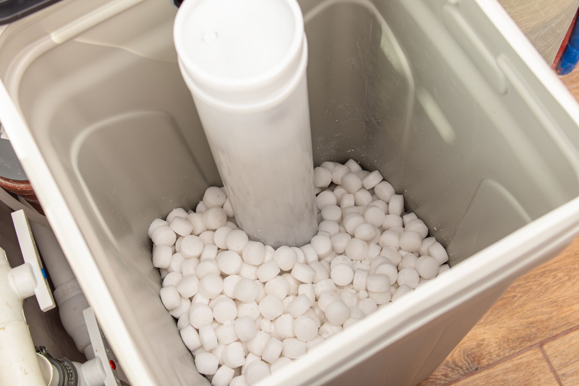 A water softener tank filled with white salt pellets and a central white tube.