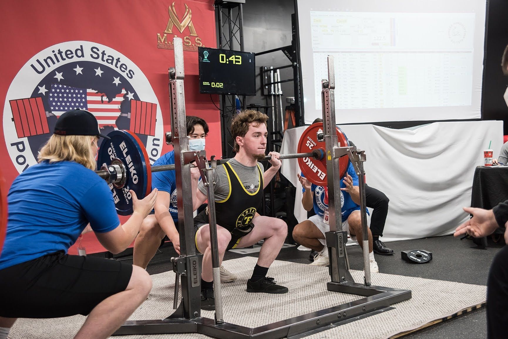 A group of people are squatting down in a gym.