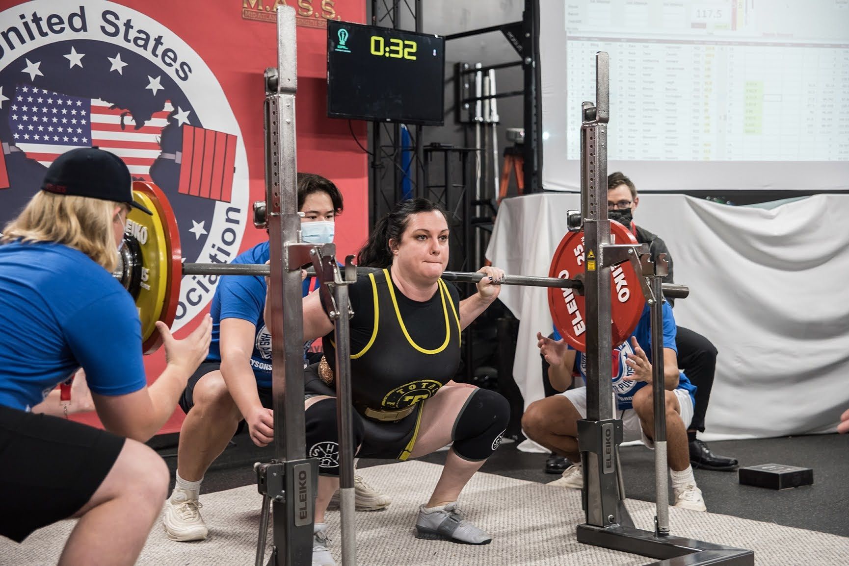 A woman is squatting with a barbell in a gym.