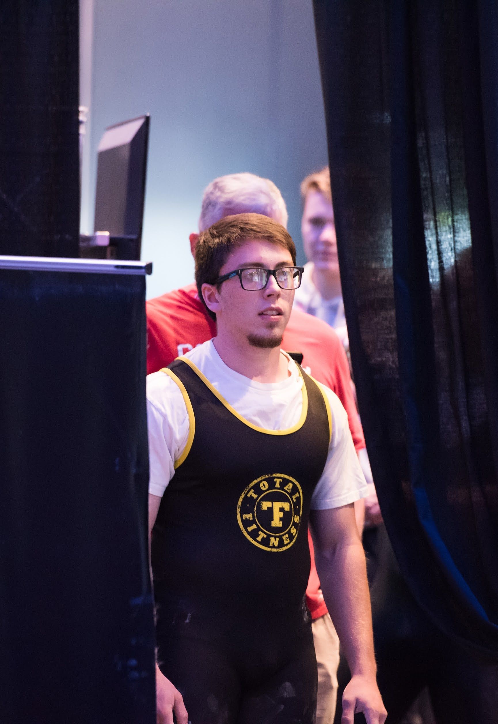 A man wearing glasses and a tank top with the letter f on it