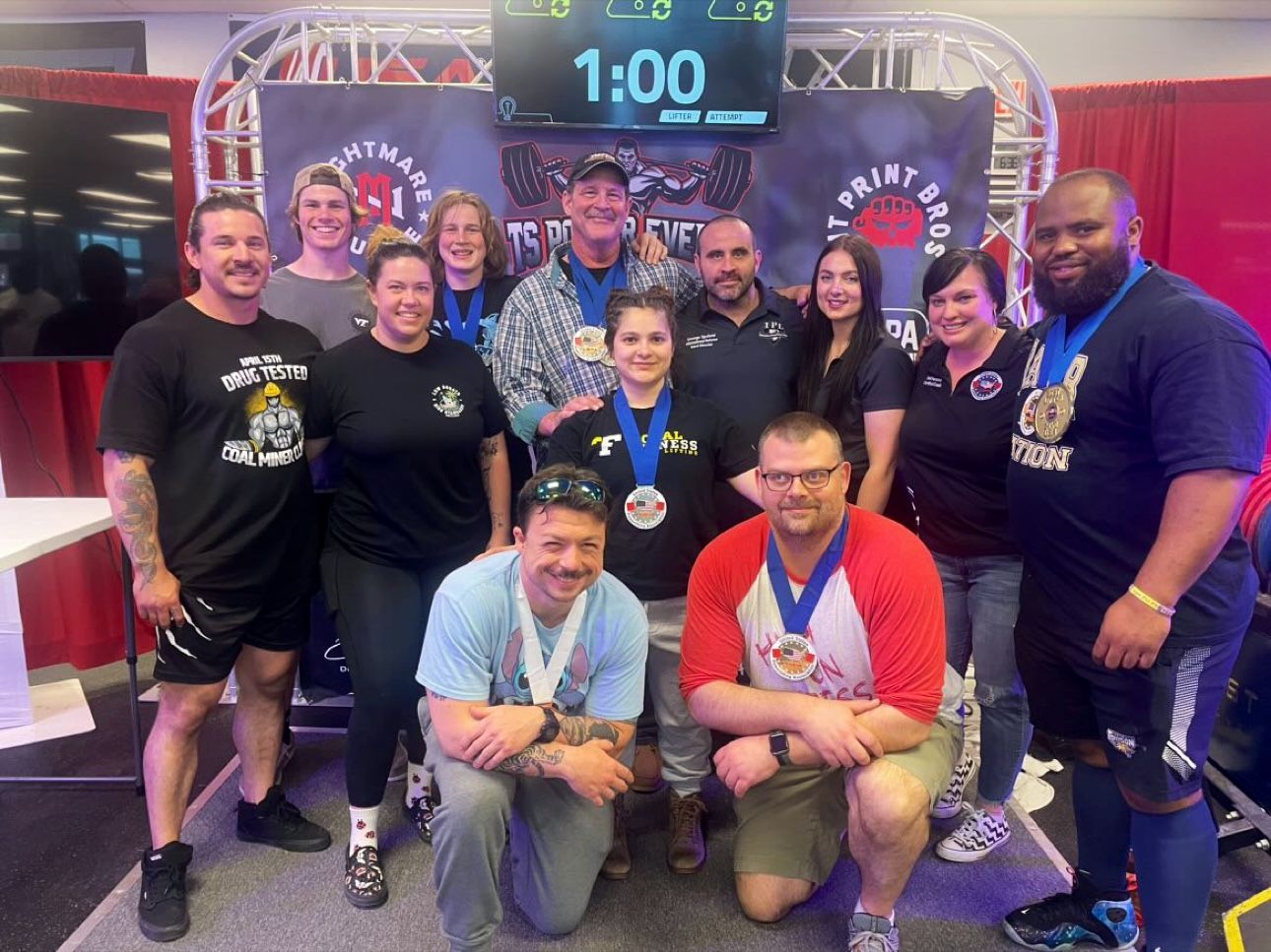 A group of people posing for a picture in front of a scoreboard that says 1:00