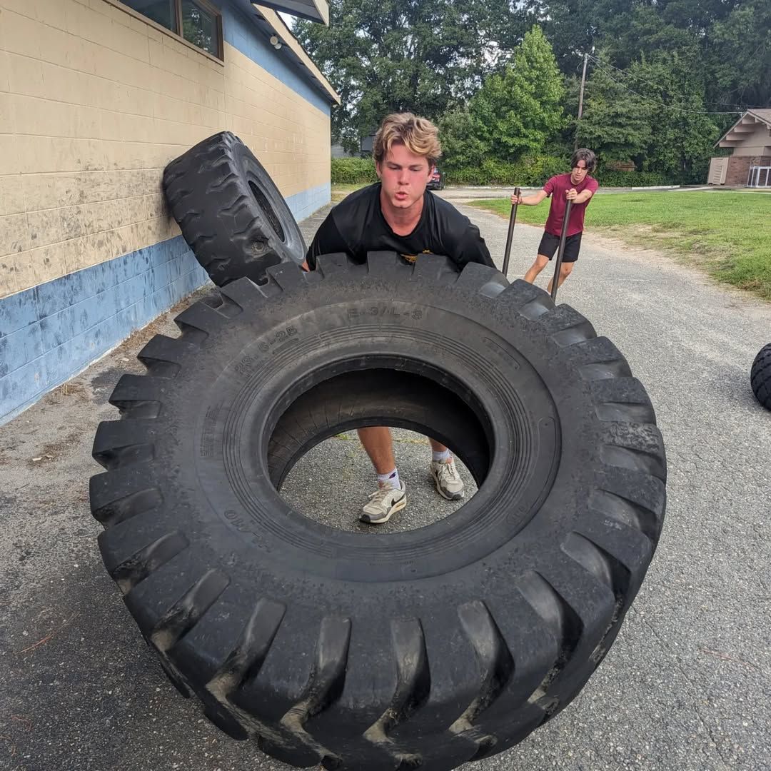 A man is pushing a large tire on the ground
