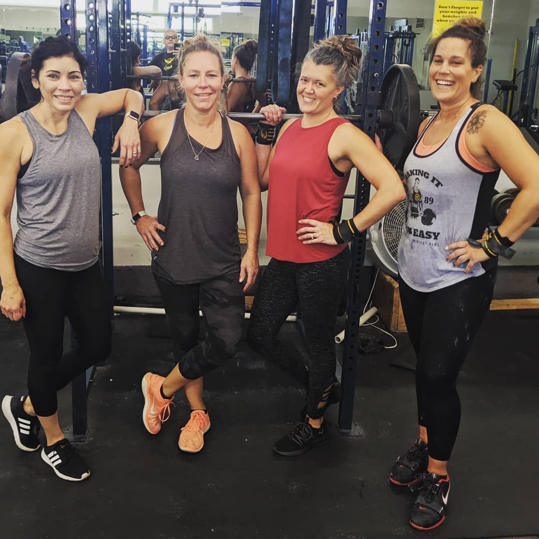 A group of women are posing for a picture in a gym