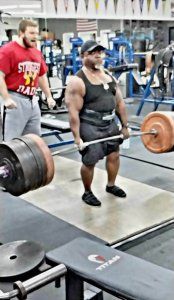 A man is lifting a barbell in a gym.