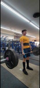 A man is lifting a barbell in a gym.