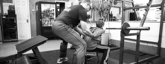 A man is doing push ups in a gym in a black and white photo.