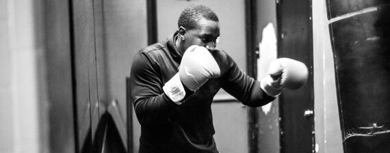 A man is wearing boxing gloves inside a gym.