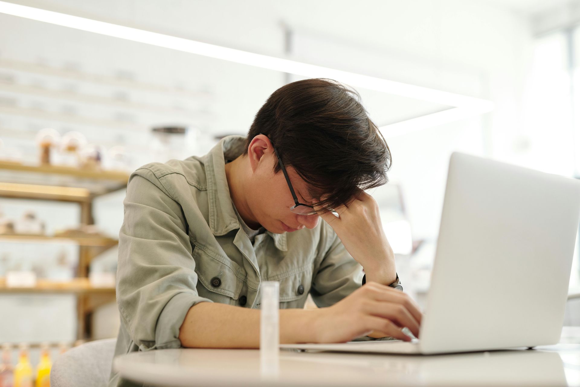 A man is sitting at a table using a laptop computer.