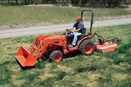 Man operating an orange tractor with a mower in a grassy field.