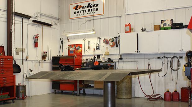 Mechanic's workshop with tools, work table, red toolboxes, and Deka Batteries sign.