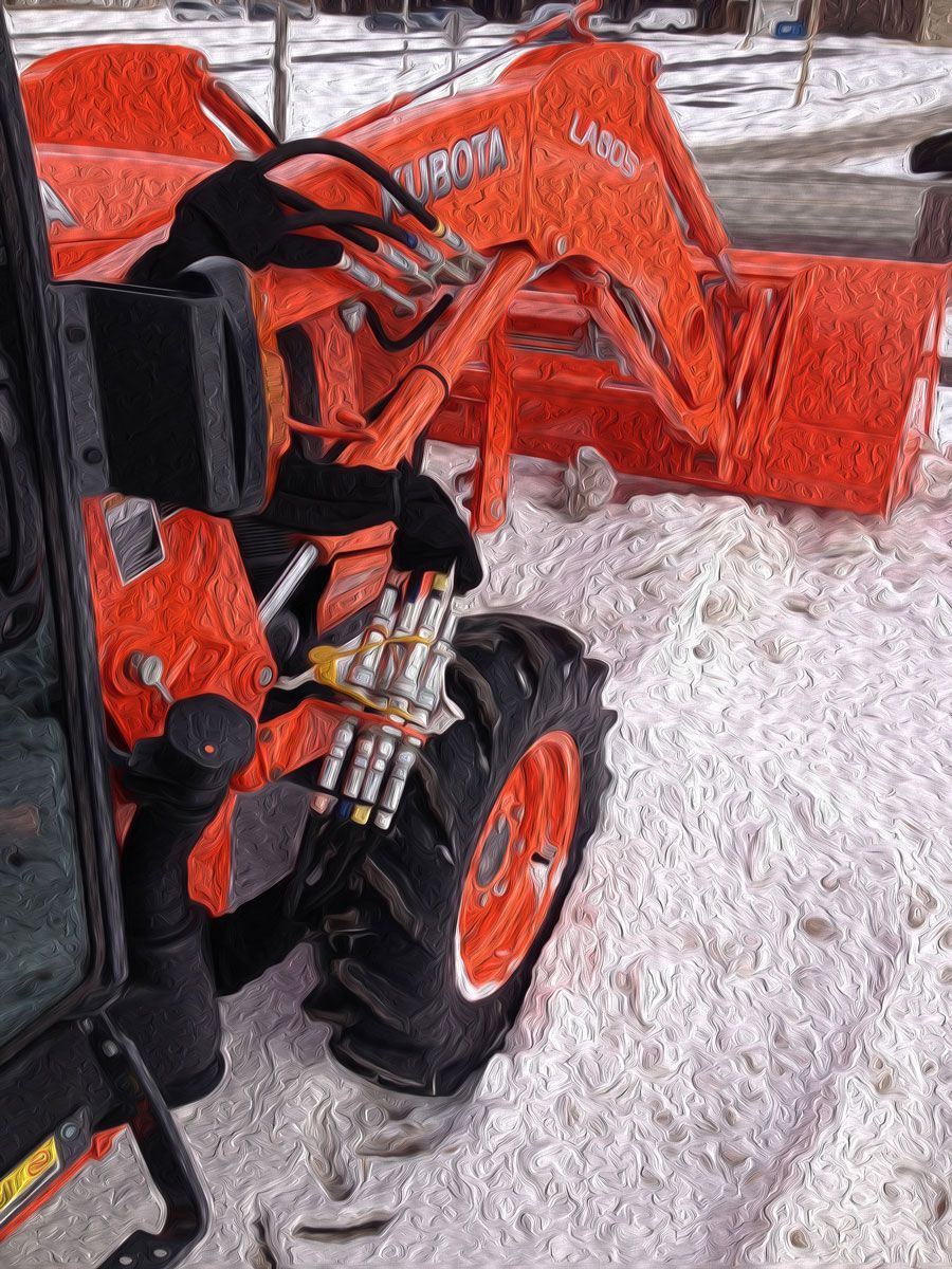 Orange Kubota tractor with a front loader, on a snowy surface.