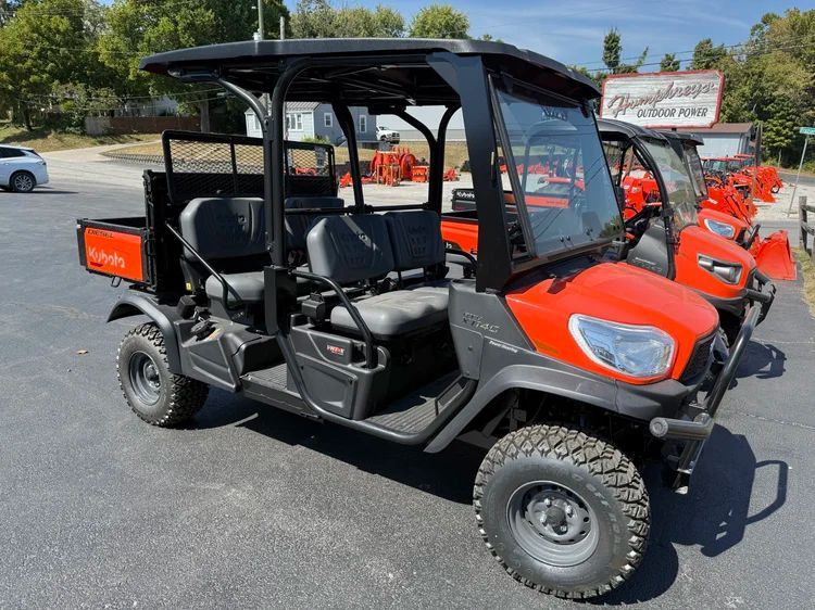 Orange and black Kubota utility vehicle parked on asphalt lot.