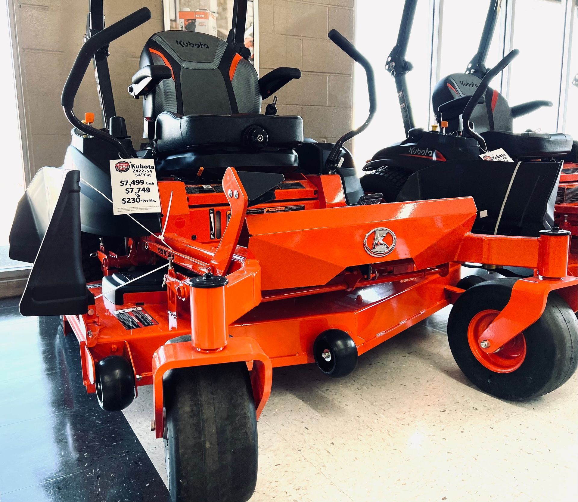Orange and black zero-turn lawn mower on display at a store.