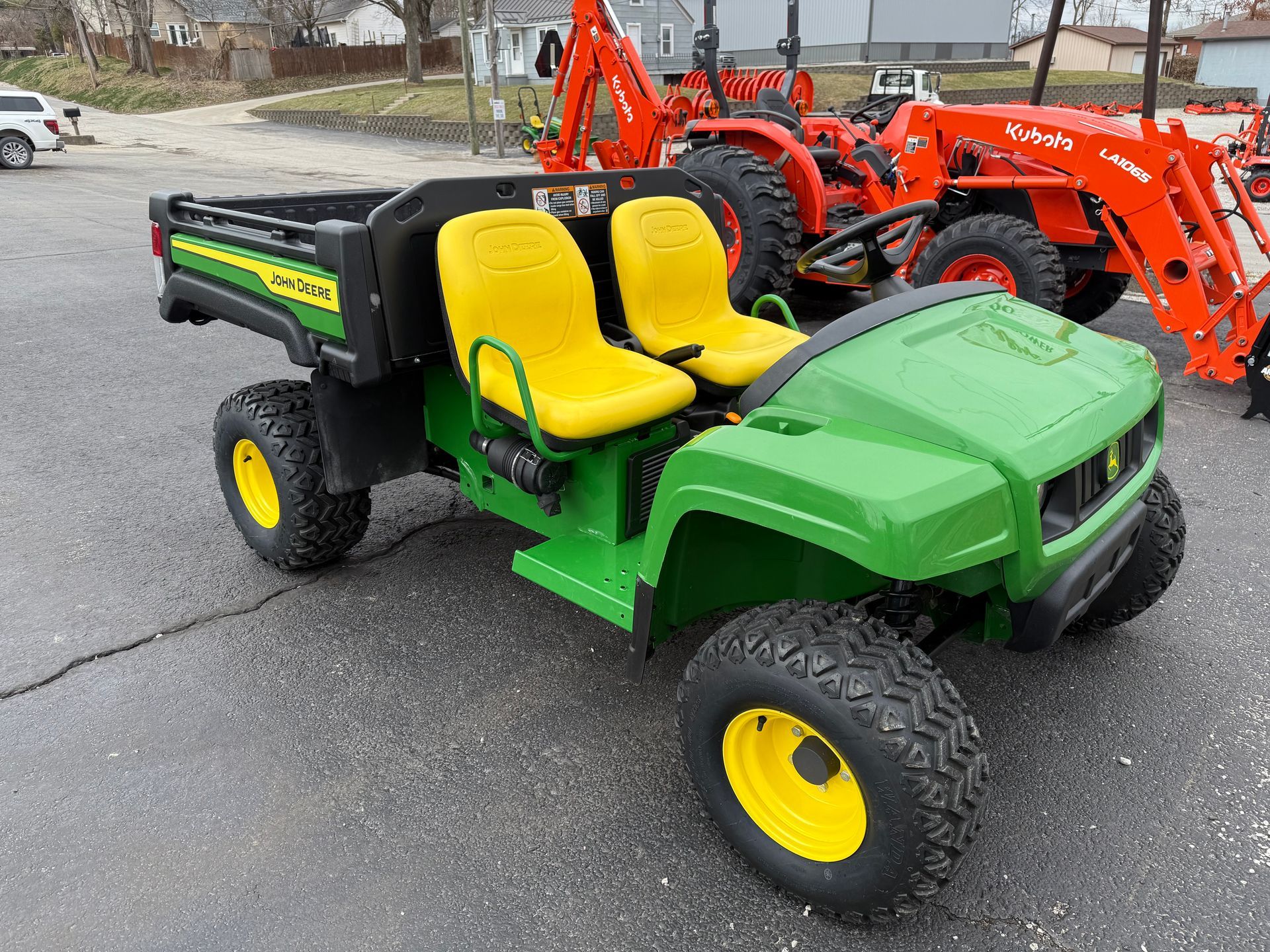 Orange tractor with front loader and backhoe parked in front of a building with a "Dixie Chopper" sign.