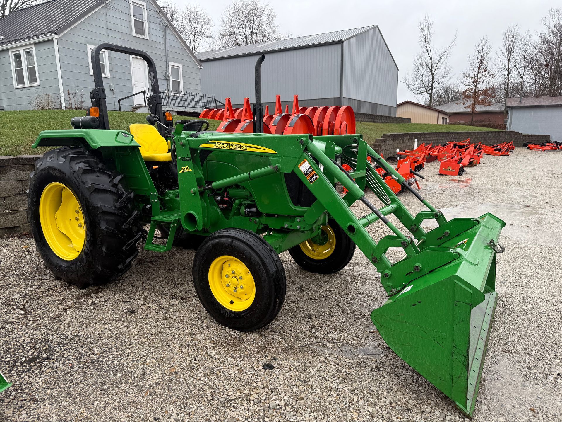Orange tractor with front loader and backhoe parked in front of a building with a "Dixie Chopper" sign.