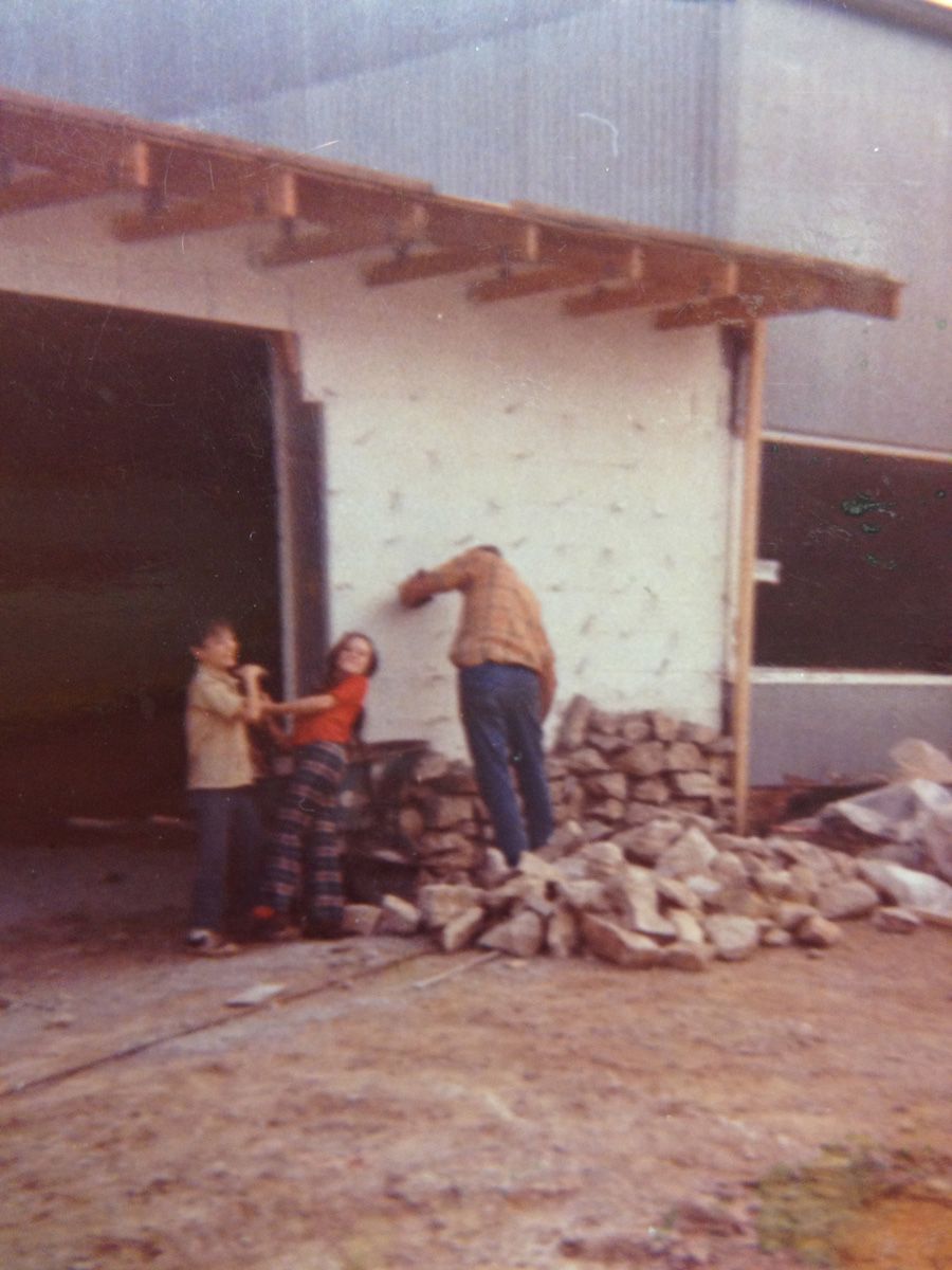 Vintage pickup truck with trailer carrying a car in front of a house.