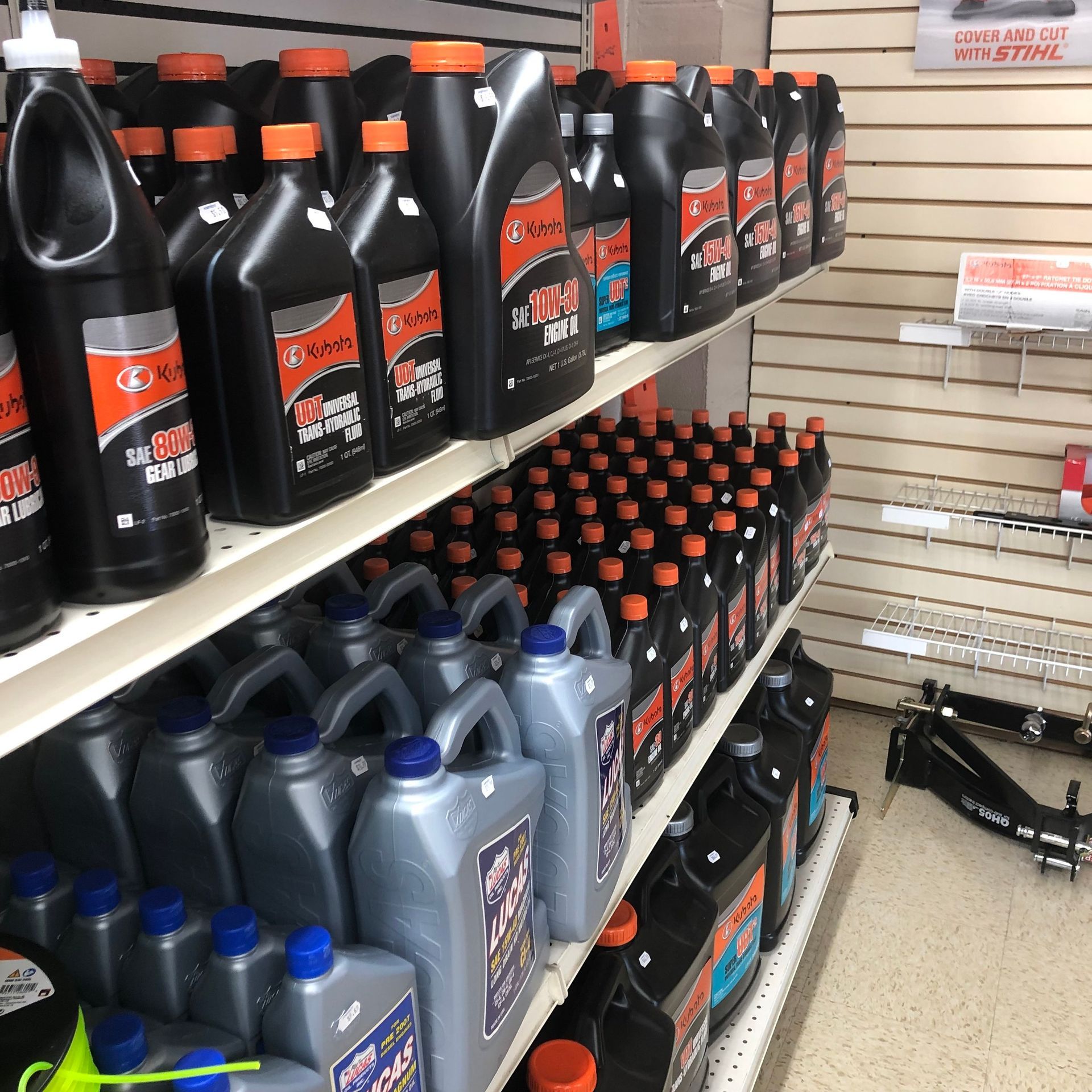 Shelves stocked with black and silver oil bottles, orange and blue caps.