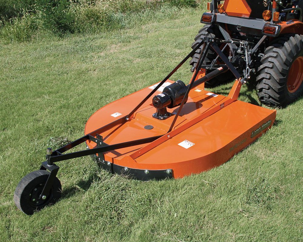 Orange tractor with a rotary cutter mowing grass.