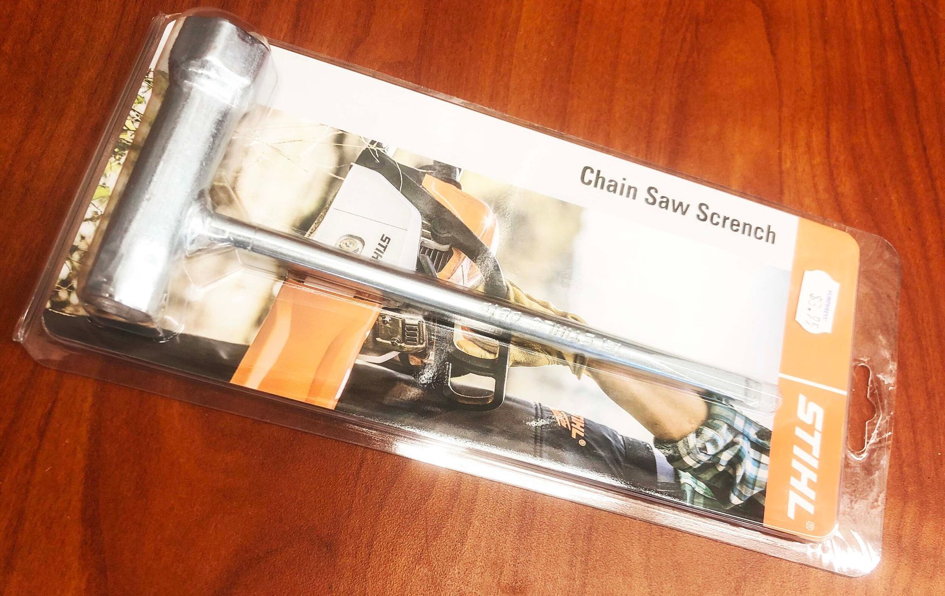 A packaged Stihl chain saw wrench on a wood surface.