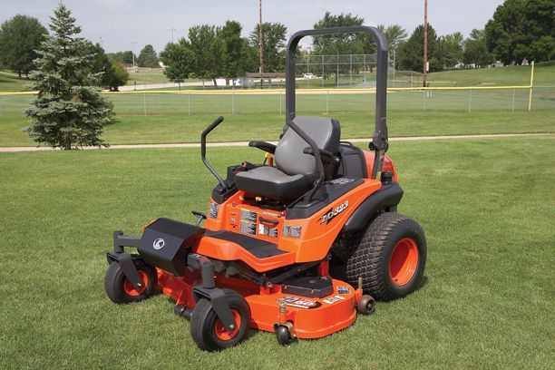 Orange Kubota zero-turn mower on a grassy lawn in a park.