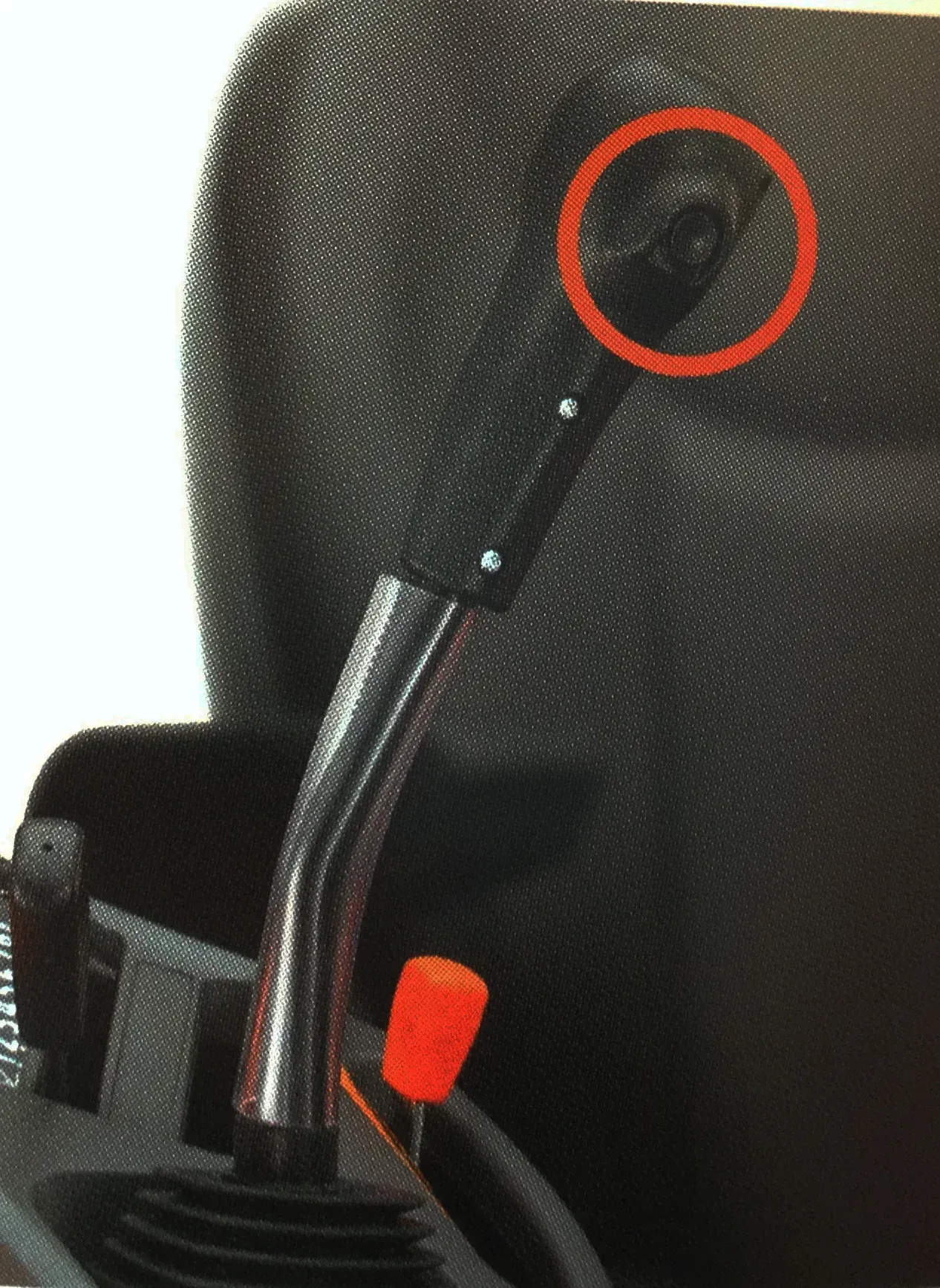 Black textured seat with a gearshift, an orange knob, and a circled hole.